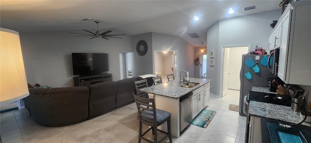 kitchen featuring visible vents, a kitchen bar, a sink, stainless steel appliances, and light stone countertops