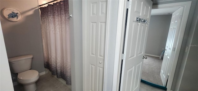 bathroom featuring a closet, curtained shower, toilet, and baseboards