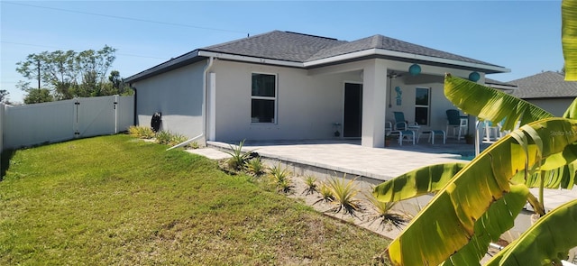 back of property featuring fence, stucco siding, a lawn, a patio, and a gate