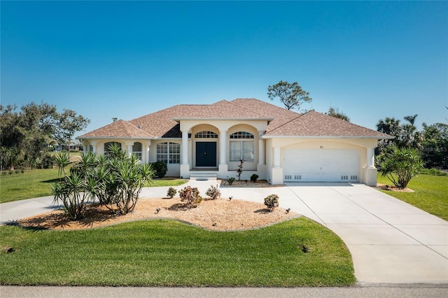 mediterranean / spanish-style home featuring stucco siding, a front lawn, concrete driveway, and a garage