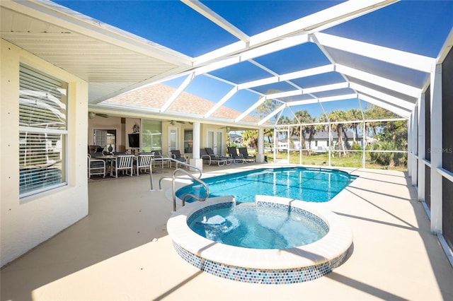 view of swimming pool featuring glass enclosure, a pool with connected hot tub, a ceiling fan, and a patio area