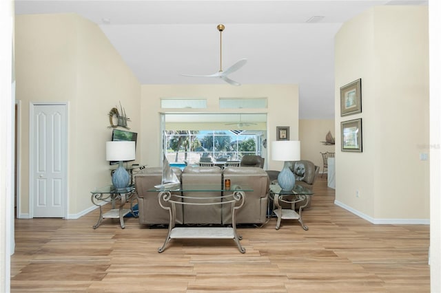 living area featuring baseboards, high vaulted ceiling, wood finished floors, and a ceiling fan