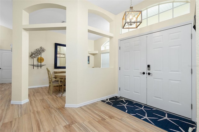 entrance foyer featuring baseboards, a notable chandelier, a high ceiling, and wood finished floors