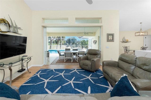 living room featuring a sunroom, baseboards, and wood finished floors