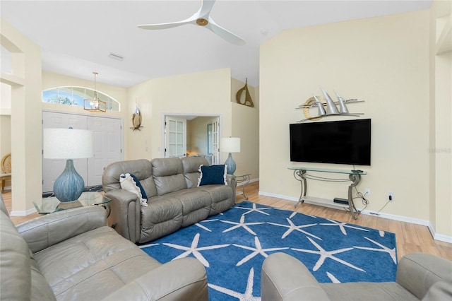 living area featuring wood finished floors, visible vents, baseboards, vaulted ceiling, and ceiling fan with notable chandelier