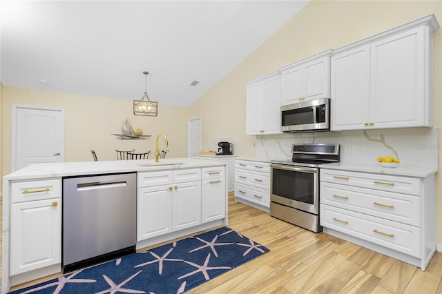 kitchen with a sink, stainless steel appliances, vaulted ceiling, light wood-style floors, and tasteful backsplash