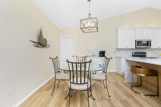 dining room featuring baseboards, light wood finished floors, a chandelier, and vaulted ceiling