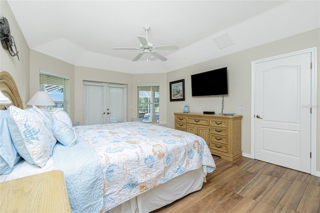 bedroom featuring baseboards, ceiling fan, light wood-style flooring, a closet, and a raised ceiling