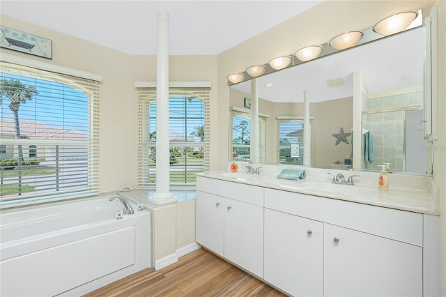 full bathroom with a sink, wood finished floors, a shower stall, double vanity, and a bath