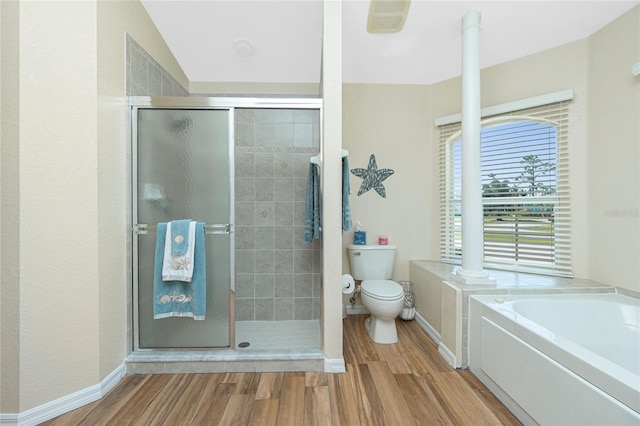 bathroom with a shower stall, baseboards, toilet, a garden tub, and wood finished floors