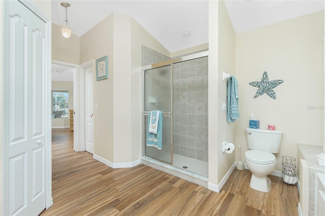 bathroom featuring a stall shower, toilet, baseboards, and wood finished floors