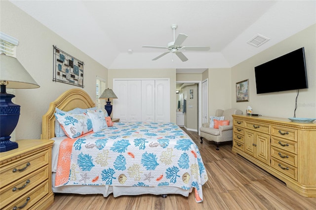 bedroom featuring visible vents, two closets, ceiling fan, vaulted ceiling, and light wood-style floors