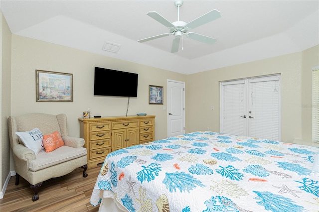 bedroom featuring visible vents, light wood finished floors, ceiling fan, a closet, and a raised ceiling