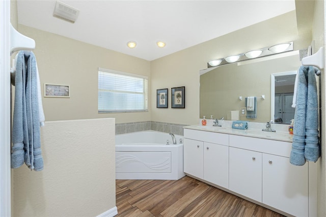 bathroom with a sink, visible vents, wood finished floors, and double vanity