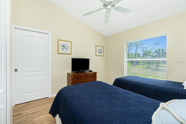 bedroom with ceiling fan, baseboards, light wood-style flooring, and vaulted ceiling