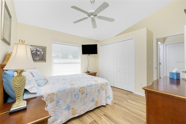 bedroom featuring light wood finished floors, baseboards, ceiling fan, lofted ceiling, and a closet