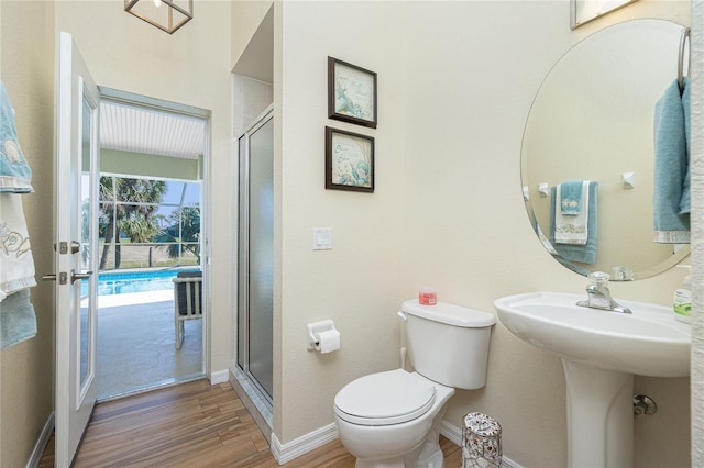 full bath featuring toilet, a sink, wood finished floors, a shower stall, and baseboards