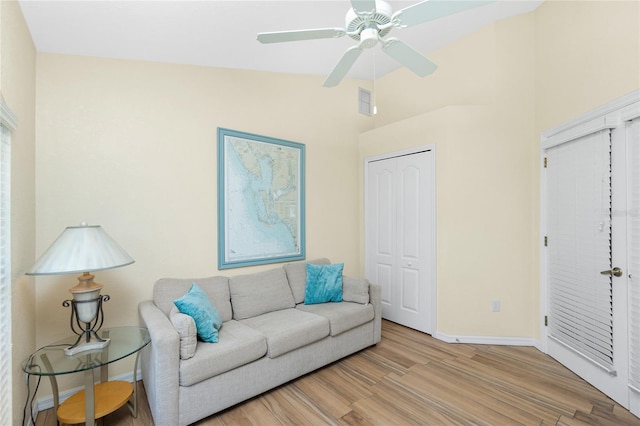 living room with visible vents, baseboards, light wood finished floors, ceiling fan, and vaulted ceiling