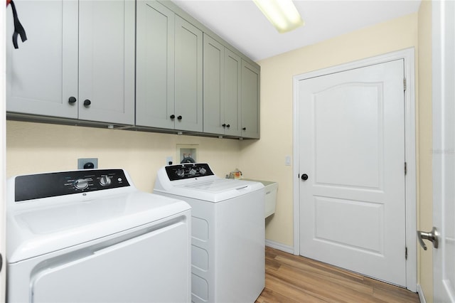 clothes washing area with light wood-style flooring, cabinet space, and independent washer and dryer