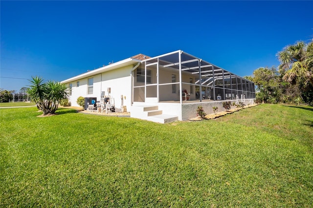 rear view of house with a lanai, a patio area, stucco siding, and a yard