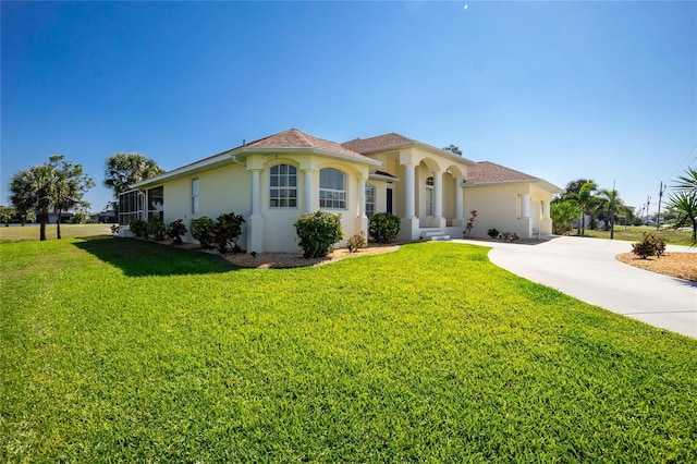 mediterranean / spanish-style home with stucco siding, driveway, and a front lawn