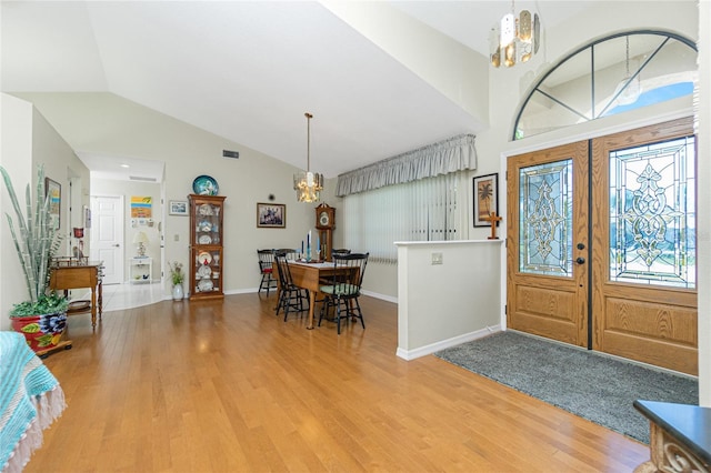 entryway with visible vents, a notable chandelier, high vaulted ceiling, light wood-style flooring, and french doors