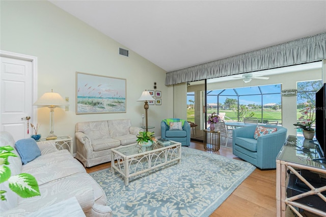 living room with visible vents, high vaulted ceiling, wood finished floors, and a sunroom