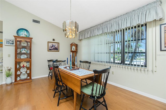 dining space featuring visible vents, light wood-style flooring, an inviting chandelier, and vaulted ceiling