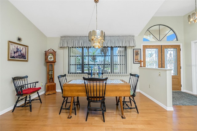 dining area featuring a notable chandelier, baseboards, lofted ceiling, and light wood-style floors