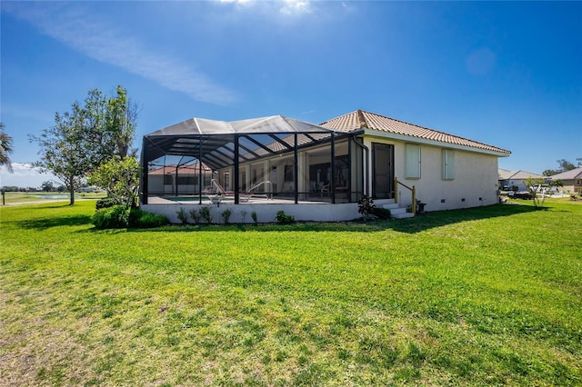 rear view of house featuring stucco siding, a lawn, a lanai, and a tile roof