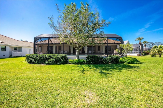 rear view of property with a lanai and a lawn