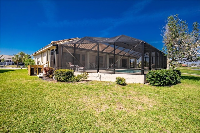 rear view of house featuring an outdoor pool, a patio, a lawn, and a lanai