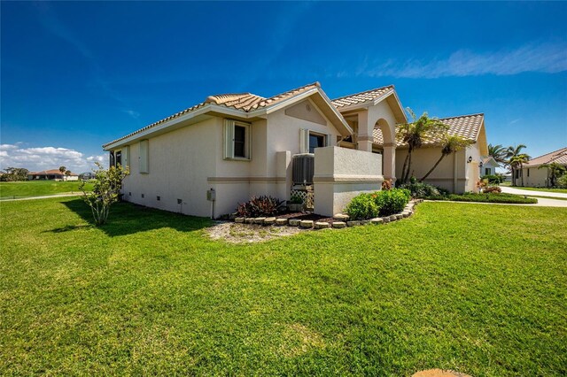 view of home's exterior featuring crawl space, stucco siding, a tiled roof, and a lawn