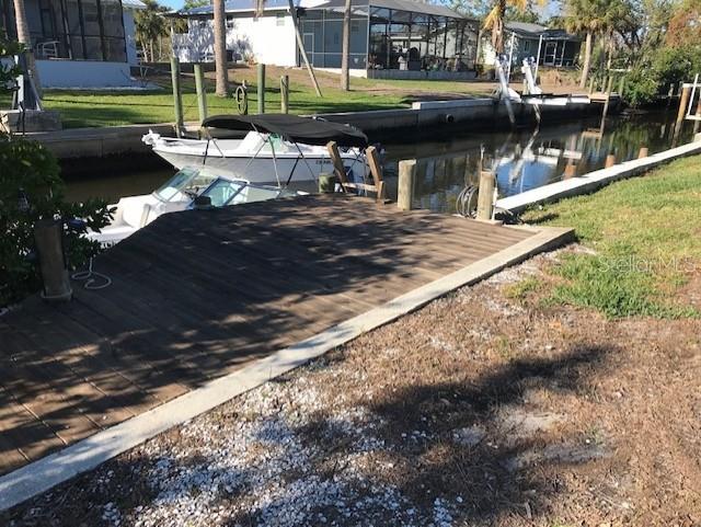 view of dock with a lanai, a yard, and a water view