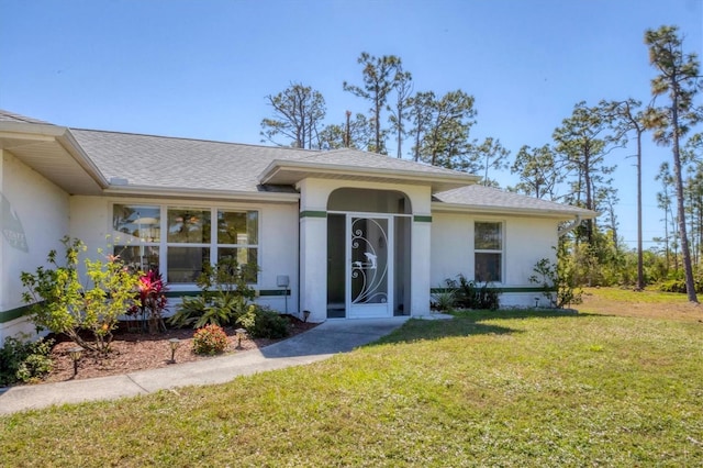 doorway to property with stucco siding, a lawn, and a shingled roof