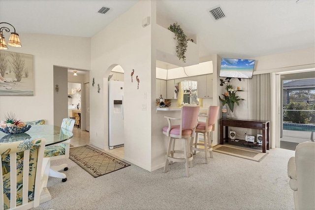 interior space featuring visible vents, arched walkways, white refrigerator with ice dispenser, and light carpet