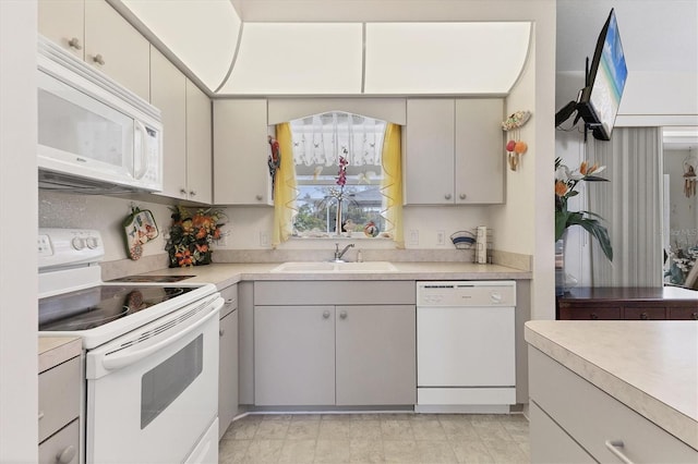 kitchen featuring a sink, white appliances, and light countertops