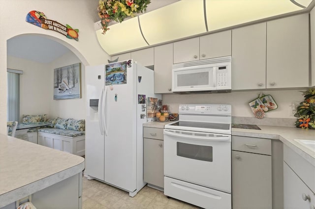 kitchen featuring arched walkways, light floors, white appliances, and light countertops