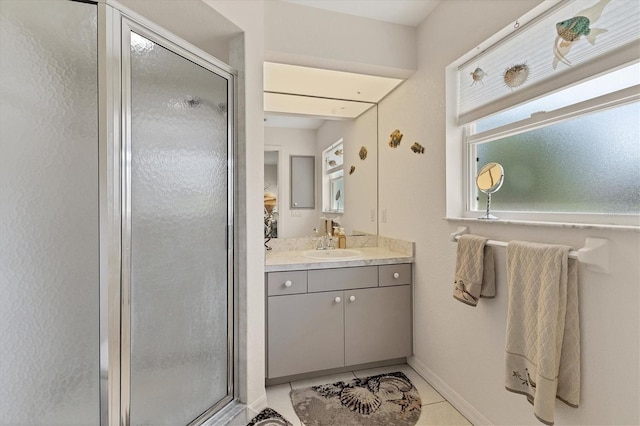 bathroom with tile patterned flooring, vanity, a stall shower, and baseboards