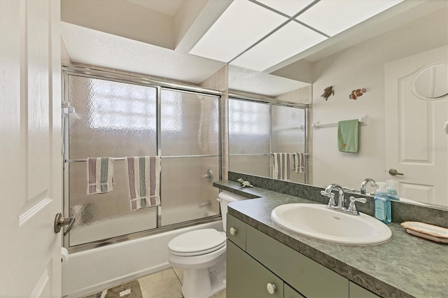 full bath with vanity, toilet, tile patterned flooring, and bath / shower combo with glass door