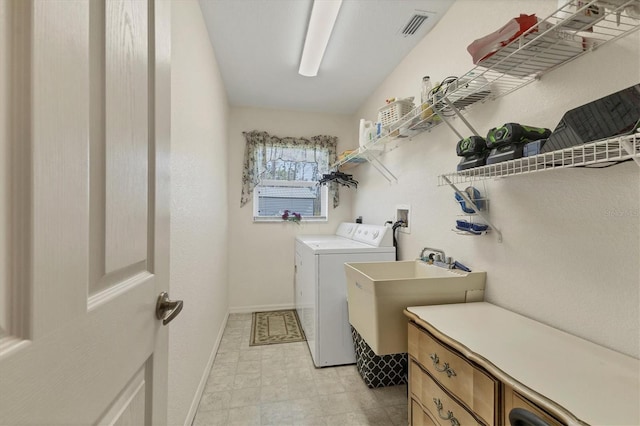 laundry area featuring visible vents, independent washer and dryer, a sink, baseboards, and laundry area