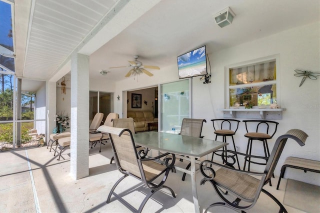 view of patio / terrace featuring outdoor dining space, a lanai, and ceiling fan