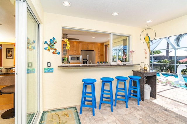 471 Capri Isles Ct, Punta Gorda, FL 33950 - kitchen with brown cabinets, a kitchen bar, appliances with stainless steel finishes, and recessed lighting