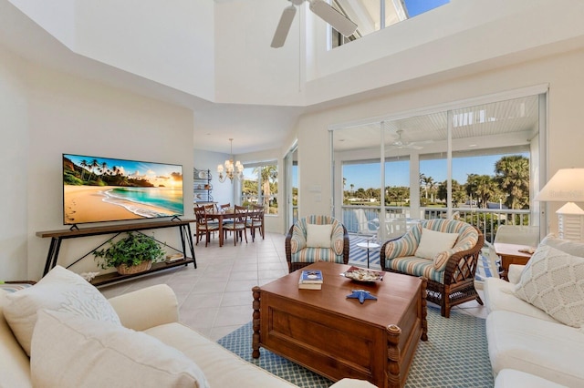 living room featuring a high ceiling, light tile patterned floors, and ceiling fan with notable chandelier