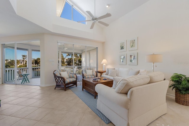 living room featuring light tile patterned floors, baseboards, a ceiling fan, and a towering ceiling