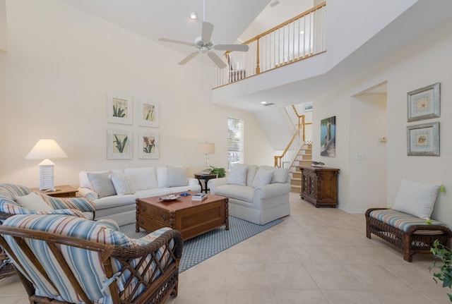 living room featuring light tile patterned floors, a ceiling fan, baseboards, stairs, and a towering ceiling