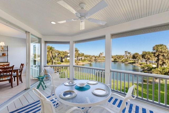 sunroom with a water view and ceiling fan