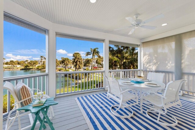 sunroom / solarium featuring a ceiling fan and a water view