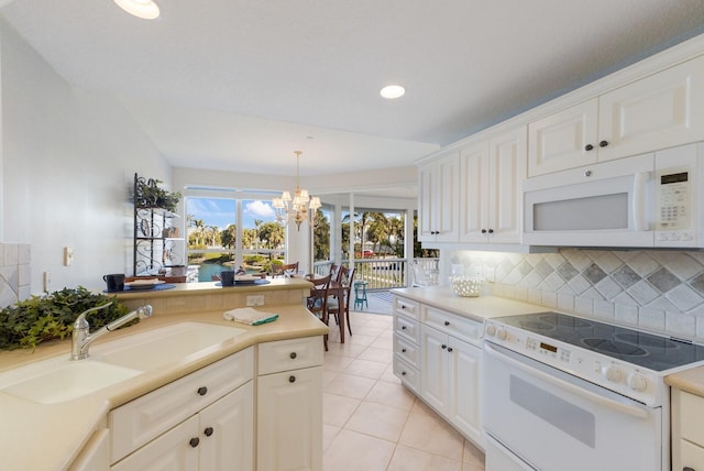 kitchen featuring a notable chandelier, a sink, tasteful backsplash, white appliances, and light tile patterned floors