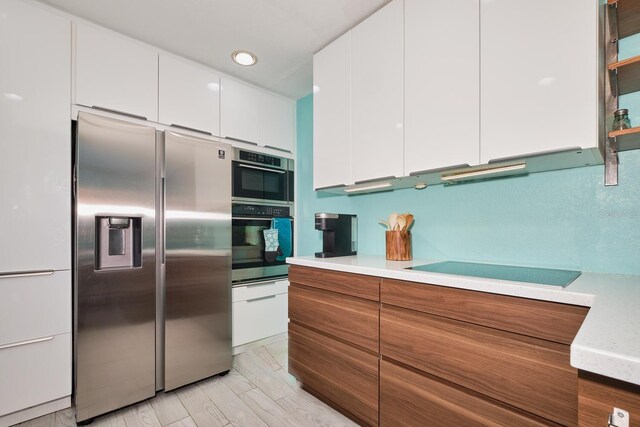 kitchen with appliances with stainless steel finishes, white cabinetry, light countertops, and modern cabinets